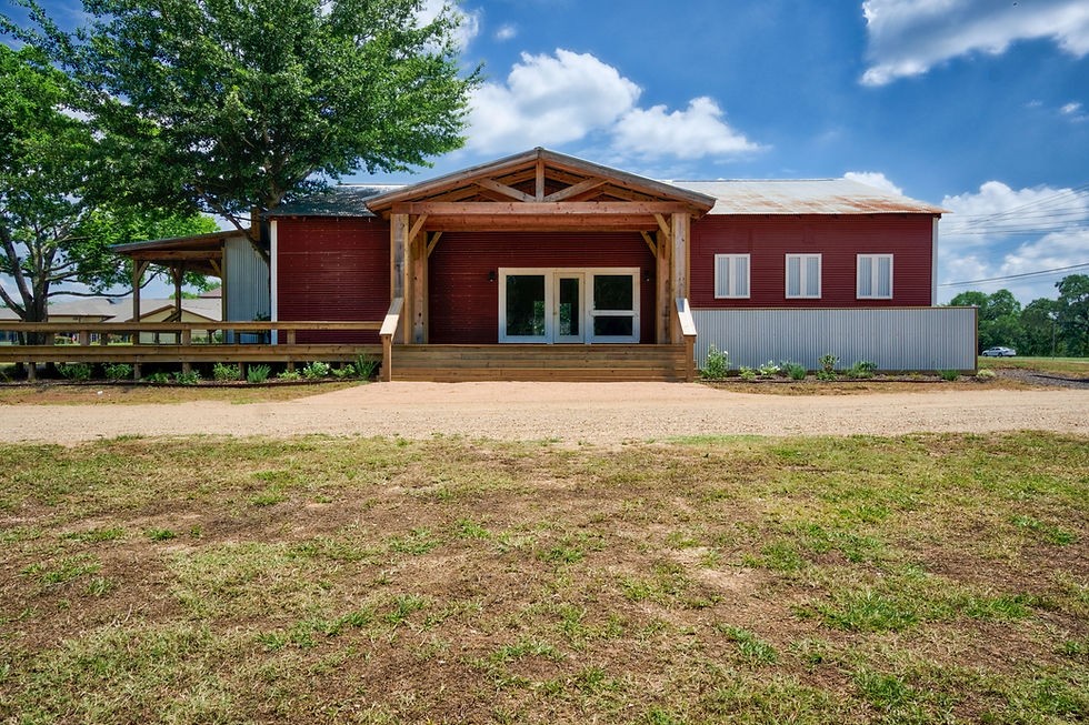 The Rebellion Barn: a red corrugated-metal barn with a timber-framed entry porch and glass doors.